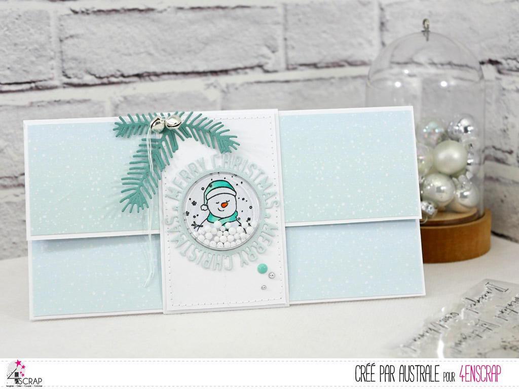 Carte porte chèque pour Noël avec bandeau à secouer, bonhomme de neige, feuillages et grelots.