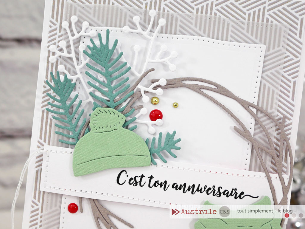 Carte d'anniversaire dans un combo de couleurs en taupe, nuances de verts et rouge, avec feuillages d'hiver, bonnet et écharpe.