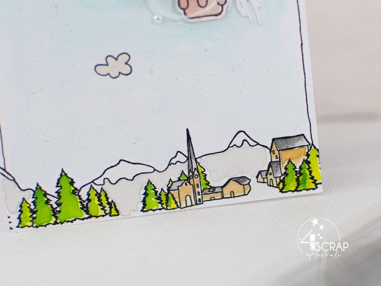 Carte avec fond paysage à l'aquarelle et une montgolfière assemblée à une étiquette, quelques feuillages, bannière et petits nuages.