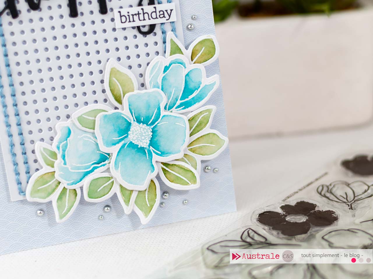 Création d'une carte d'anniversaire avec cadre brodé à la main et fleurs embossées et mises en couleurs à l'aquarelle.