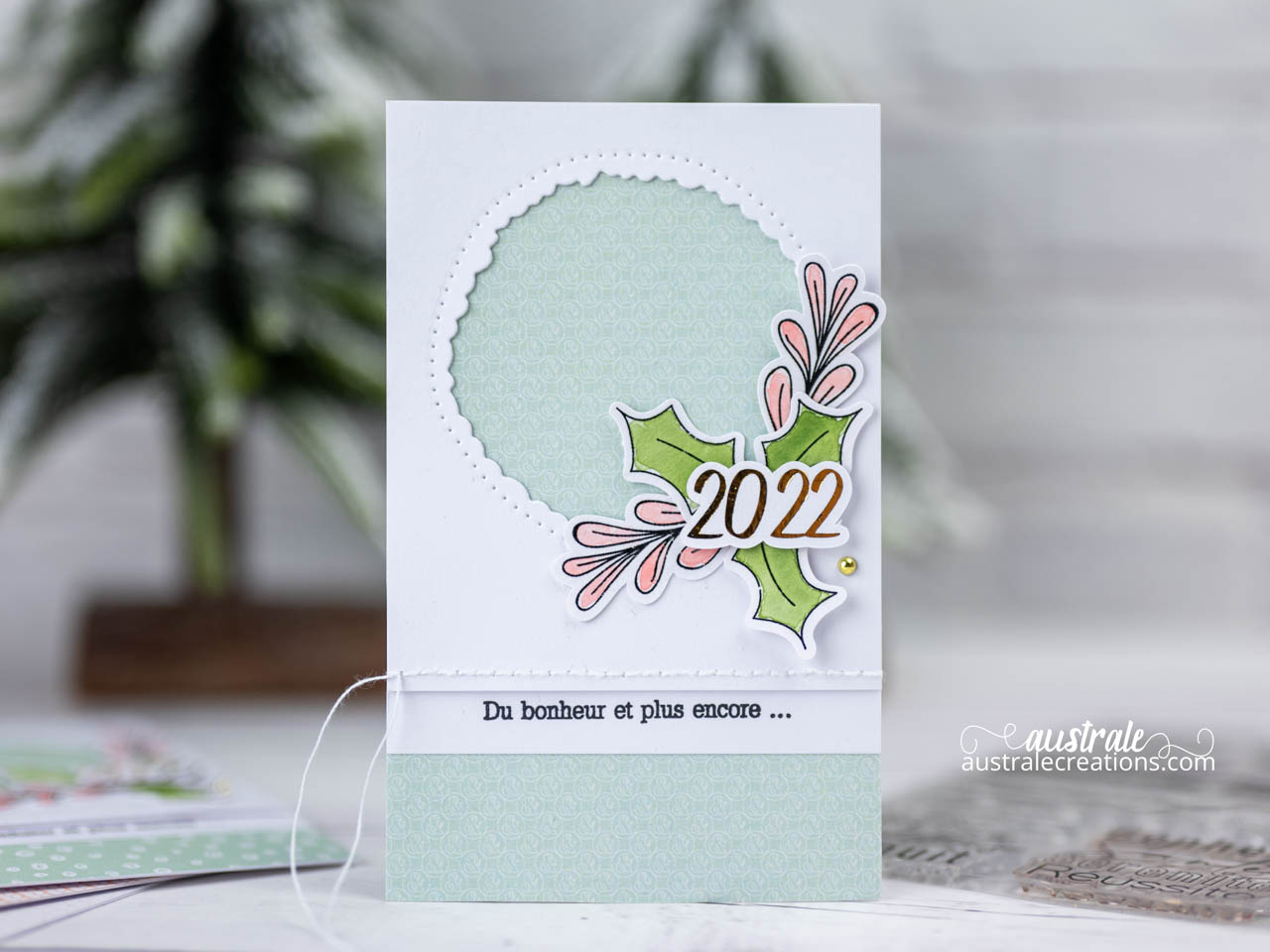 Création d'une carte de vœux en série avec tampons digitaux découpés à la Caméo et mis en couleur à l'aquarelle, l'année est embellie au foil et une fenêtre est ouverte sur les jolis papiers imprimés de 4enscrap.