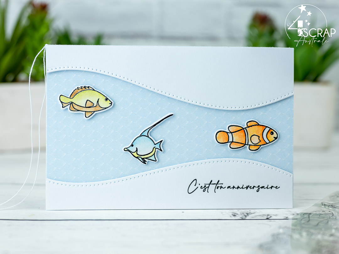 Création d'une carte d'anniversaire sur le thème Nager dans le bonheur de 4enscrap. On y voit trois petits poissons entre deux vagues.