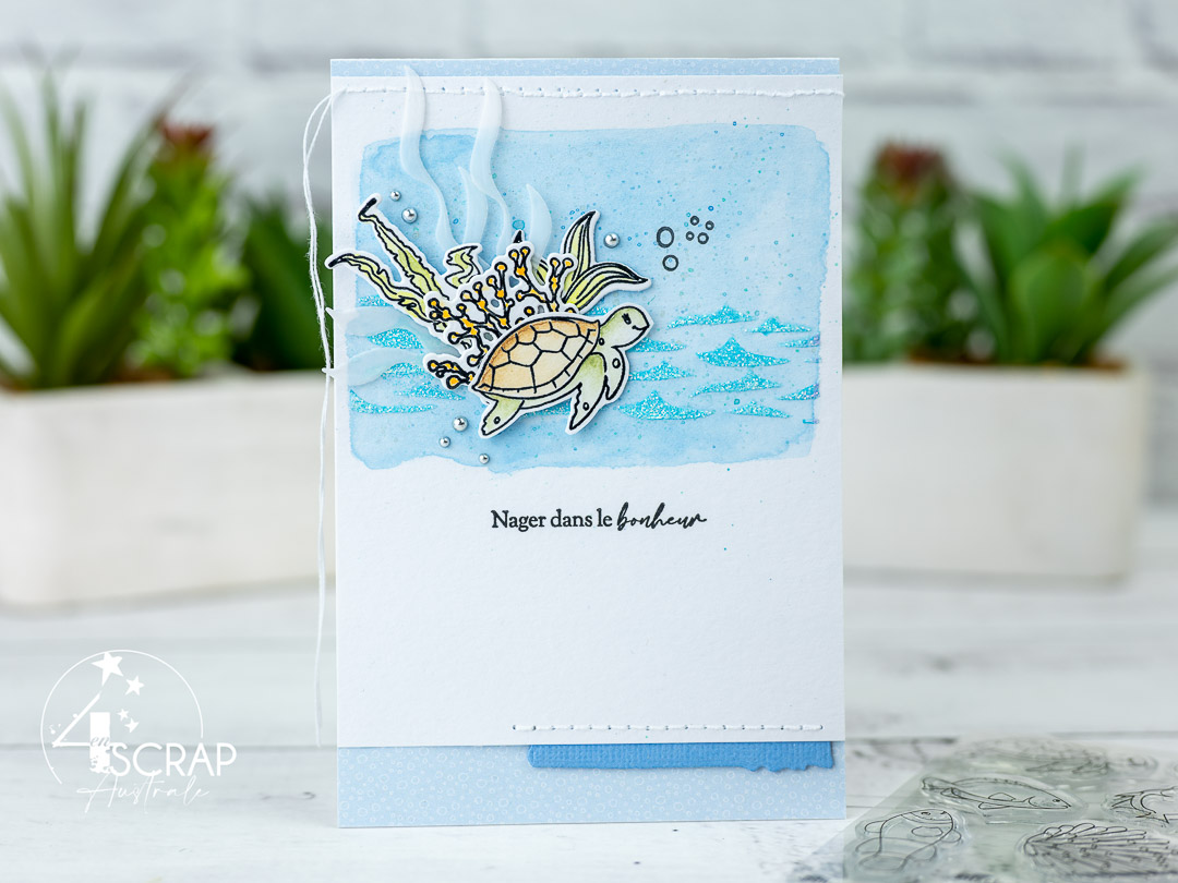 Création d'une carte sur le thème Nager dans le bonheur de 4enscrap. Le fond est réalisé à l'aquarelle avec une texture au pochoir pour les vagues. Elle est décorée d'une adorable tortue et de découpes algues.