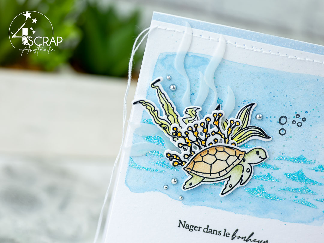 Création d'une carte sur le thème Nager dans le bonheur de 4enscrap. Le fond est réalisé à l'aquarelle avec une texture au pochoir pour les vagues. Elle est décorée d'une adorable tortue et de découpes algues.